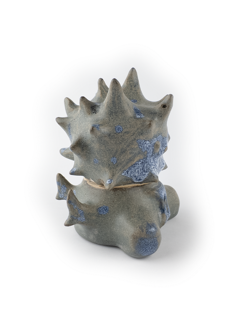 Ceramic dragon figurine with blue speckles on a white background