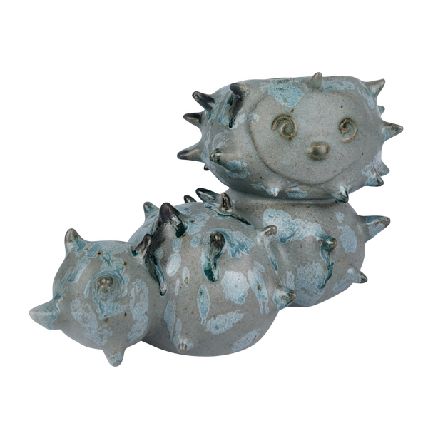 Ceramic sculpture of a sea caterpillar with a textured surface on a white background